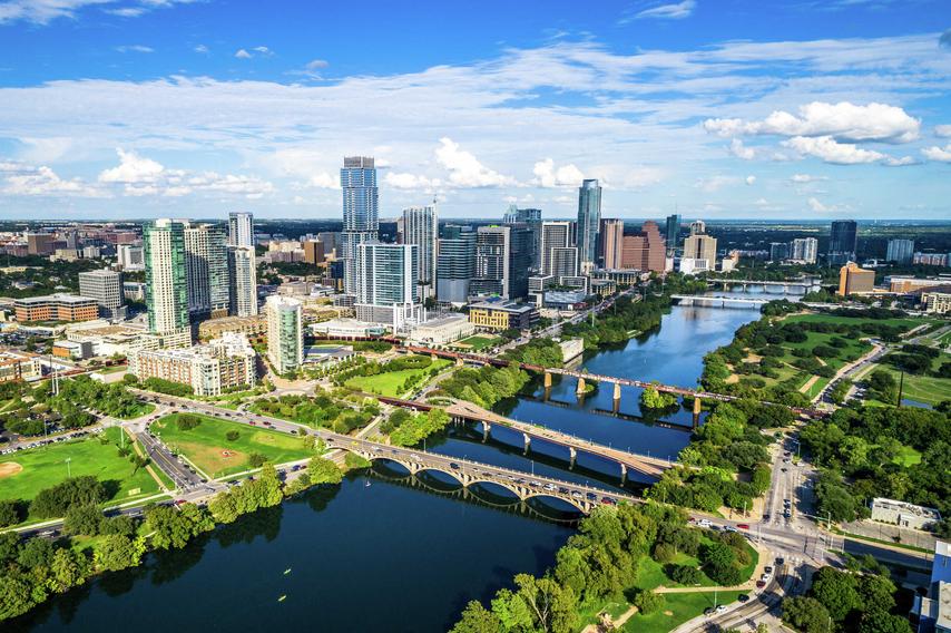 Austin, Texas cityscape taken just before sunset showing a panoramic view of the city's skyscrapers, the river flowing down the Colorado, and green parks