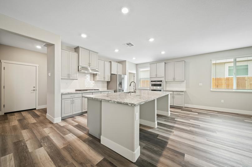 Stunning kitchen with a large granite island, tile backsplash, and wood flooring.