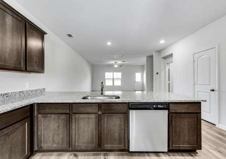 Open-concept kitchen with stainless steel appliances, brown cabinets and granite countertops. 