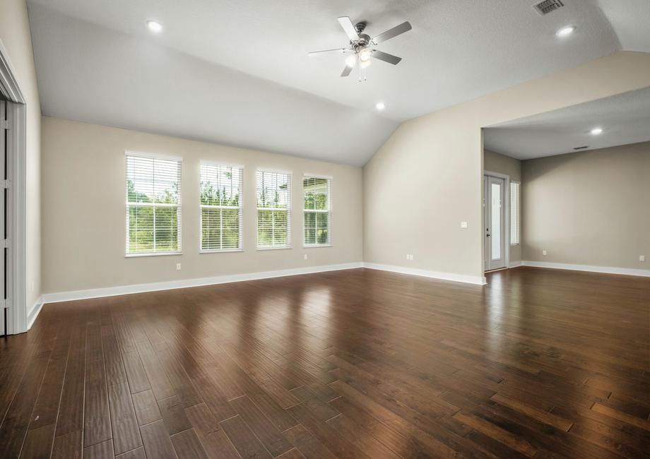 Living room with wood floor, lots of windows and a ceiling fan.