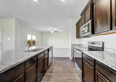 Rio finished kitchen with brown cabinets, hardwood floors, and light colored granite countertops