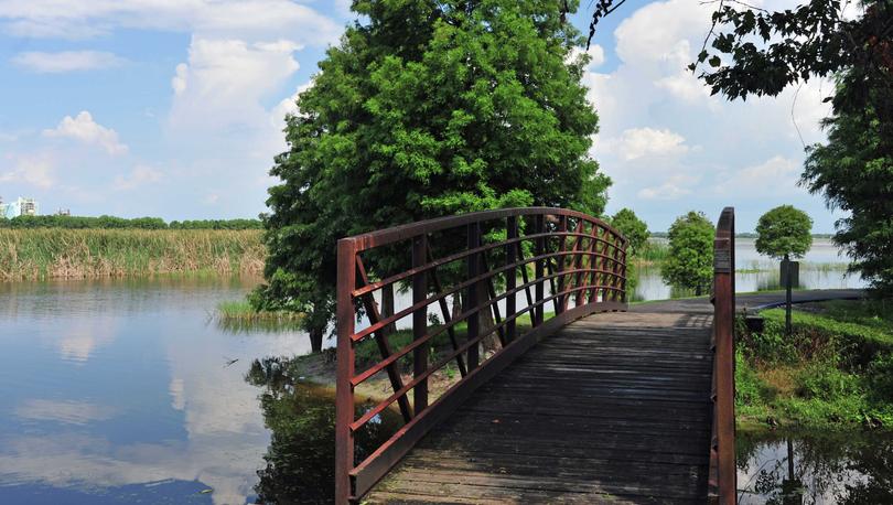 Lakeland, Florida Lake Parker showing still lake water and green trees covering a walkway bridge along a path