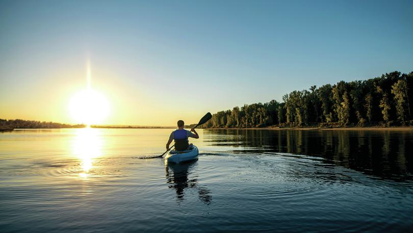 Man in kayak on river at sunset.