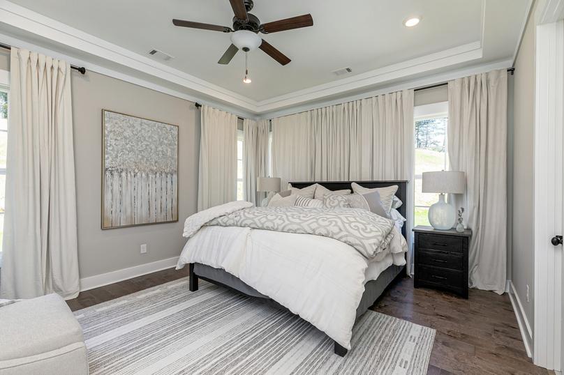 Master bedroom with wood flooring, windows and ceiling fan.