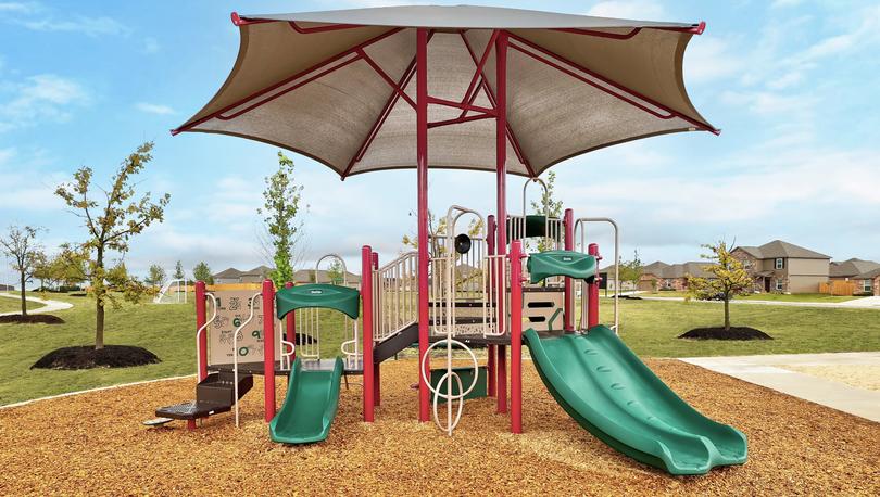 Playground with a green slide and trees in the background.