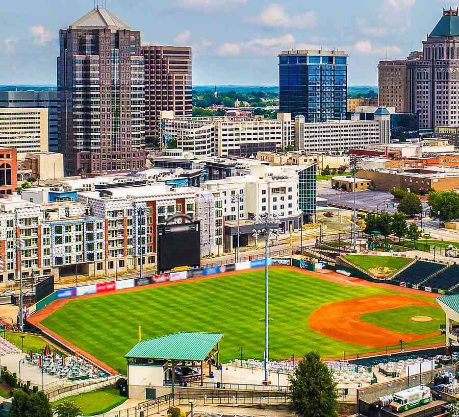 Downtown Greensboro, North Carolina cityscape photo taken from the sky showing skyscrapers, sports grounds, and apartment buildings