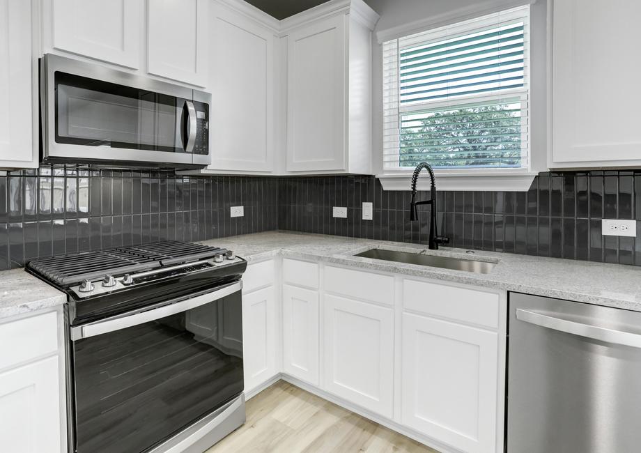 Gorgeous kitchen with tile backsplash, granite countertops, and faux wood blinds.