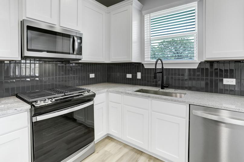 Gorgeous kitchen with tile backsplash, granite countertops, and faux wood blinds.