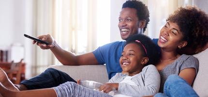 Stock photo of a family watching television together at home.