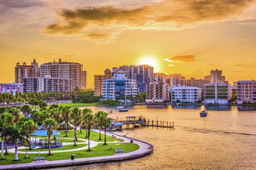 Sarasota, Florida skyline at sunset showing park with walkways, bay with boats in the water, and condos in the background