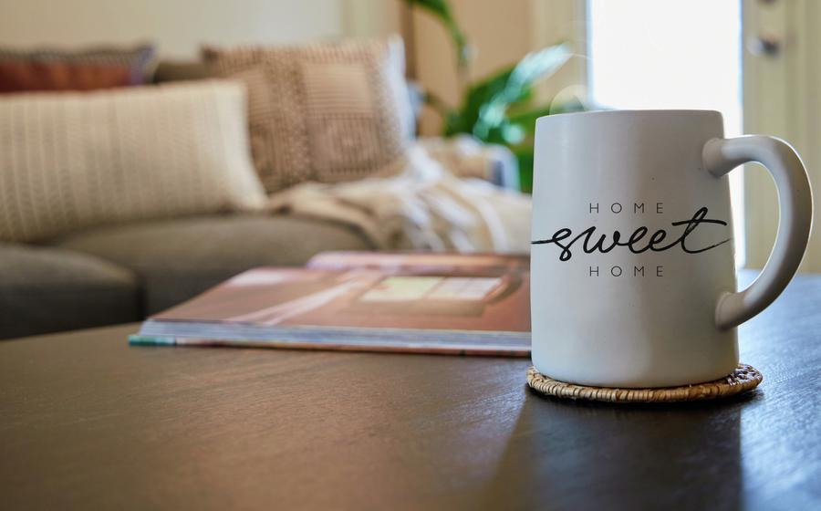 Home sweet home coffee mug on coffee table with couch in the background. 