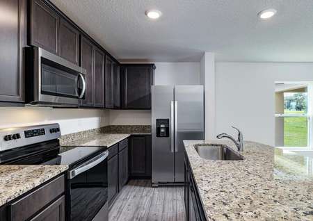 Chef-ready kitchen features granite countertops, upper-wood cabinets and stainless steel appliances. 