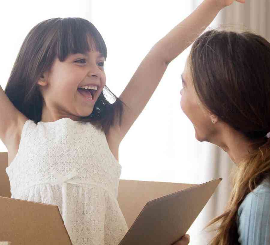 Family unpacking boxes, happy girl with arms in air