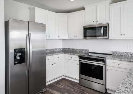 Chef-ready kitchen complete with white cabinetry with hardware, stainless steel appliances and vinyl flooring.