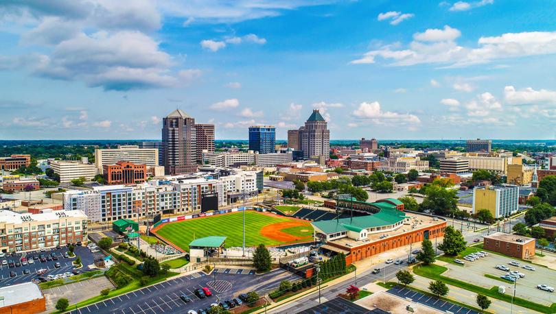 Downtown Greensboro, North Carolina cityscape photo taken from the sky showing skyscrapers, sports grounds, and apartment buildings