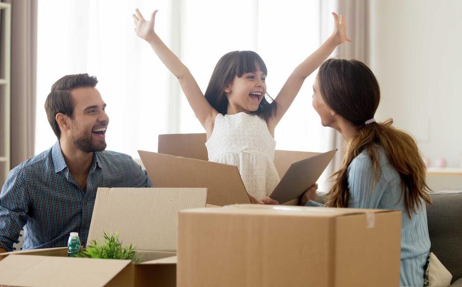 Family unpacking boxes, happy girl with arms in air