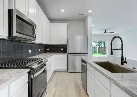 Upgraded kitchen showcasing white cabinets with crown molding and a full suite of stainless steel appliances.