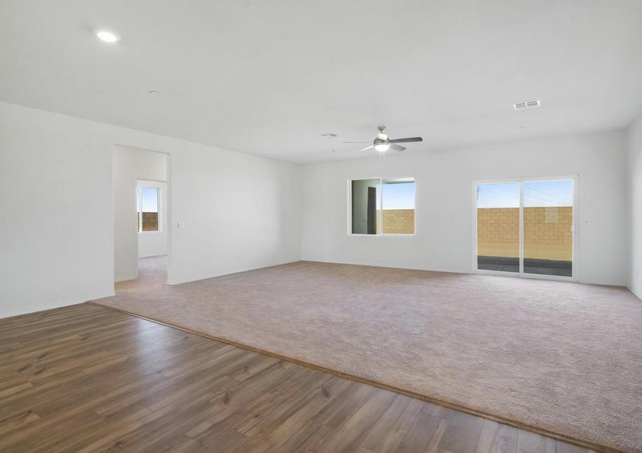 The spacious family room has a ceiling fan and carpet. 
