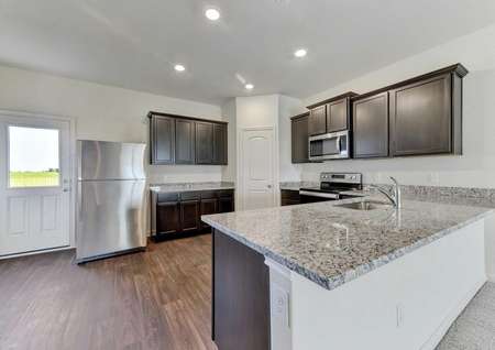 Travis kitchen with wood flooring, brown cabinetry, and stainless steel appliances