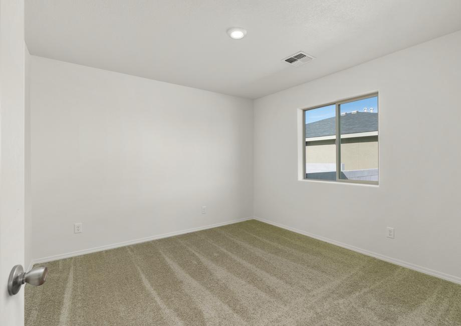 Guest bedroom with tan carpet and recessed lighting.