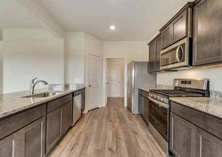 The kitchen has sprawling granite countertops, brown cabinetry and stainless steel appliances.