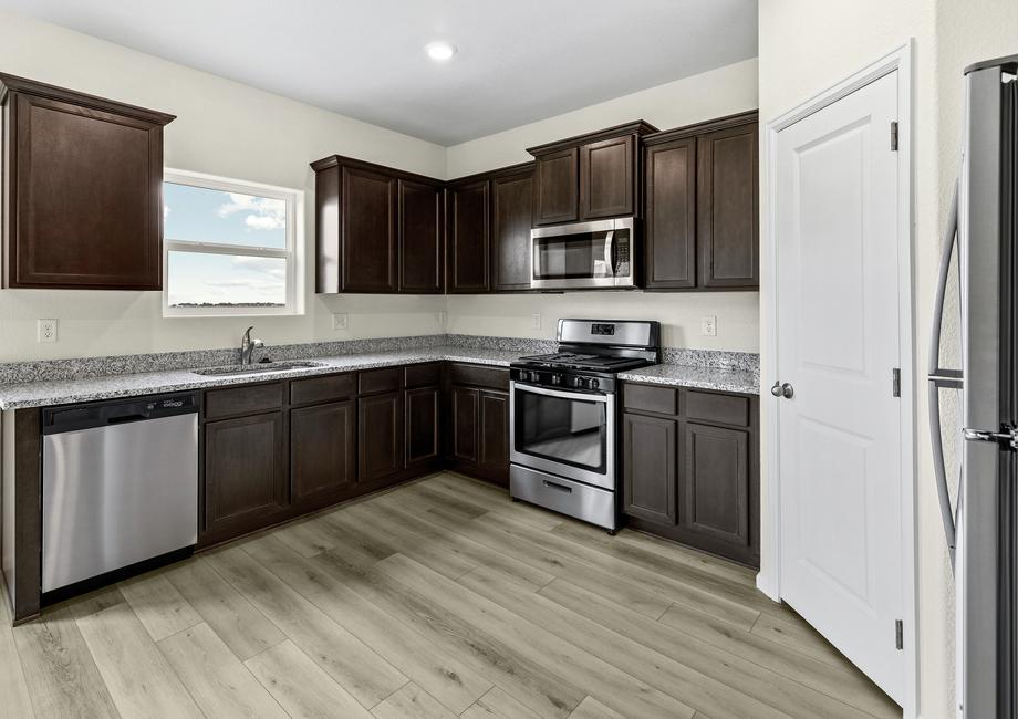 The designer kitchen features stainless appliances, granite countertops, and wood cabinetry.