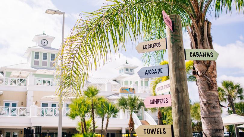 Signs with arrows pointing to various locations at a resort such as lockers, cabanas, arcade, sundries and towels. 