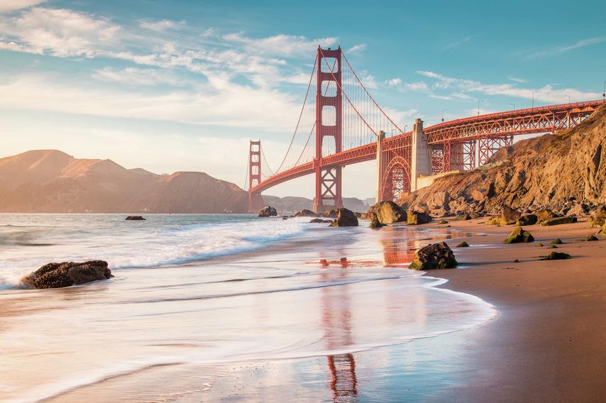 Bay Area, California San Francisco Golden Gate Bridge taken from the beach below showing waves crashing onto the sand, the suspension bridge, and rocky hills