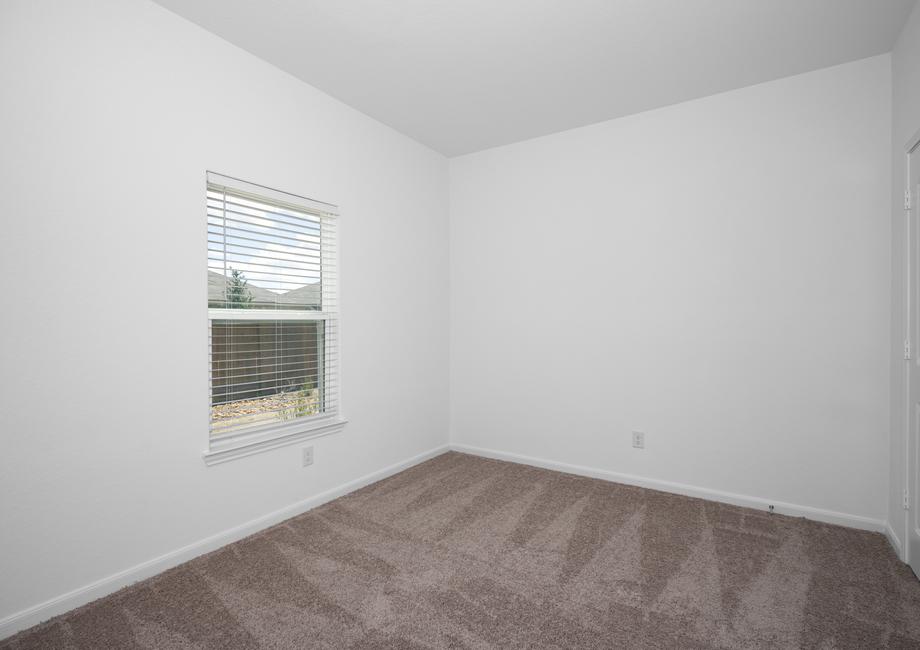 Secondary bedroom with tan carpet and a window.