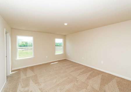 Spacious carpeted master bedroom with two windows in the Hartwell floor plan