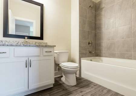 Full bathroom with granite countertops, modern hardware and luxury vinyl plank flooring.