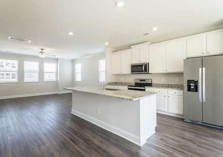 Kitchen with granite countertops, a large island, white cabinets and stainless steel appliances.