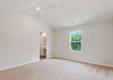 Master bedroom with a vaulted ceiling, carpet and a window.