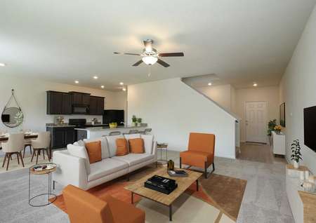 Open and spacious living room, breakfast area and kitchen decorated with beige and orange, ceiling fan and recessed lighting.