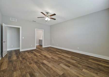 The master bedroom has beautiful hardwood flooring and a celling fan