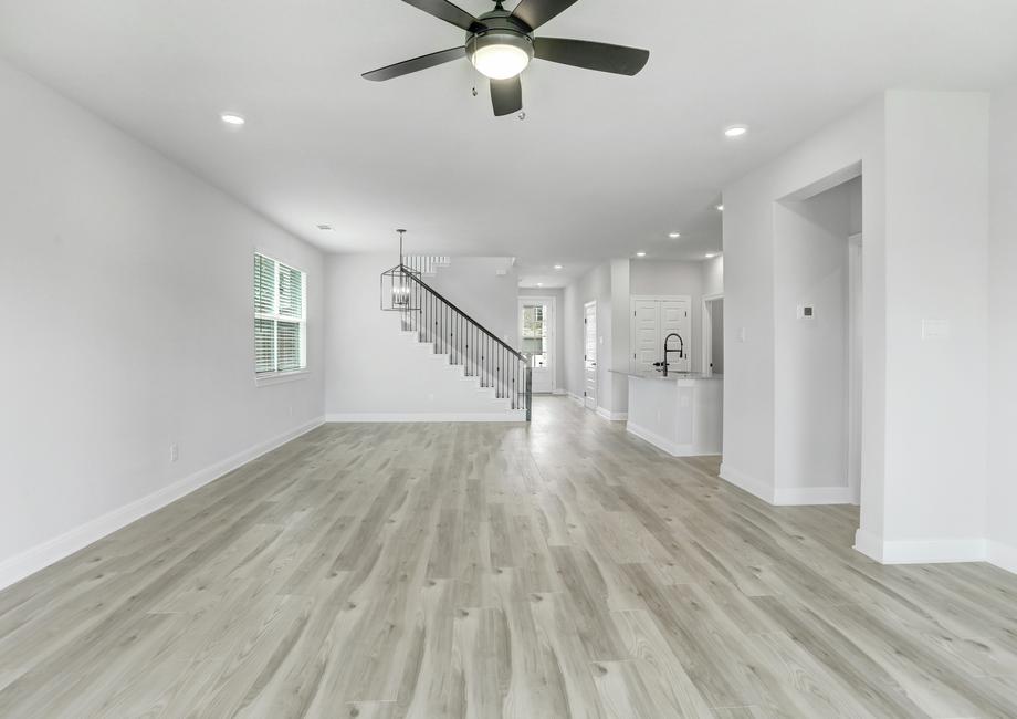 Spacious living room with a ceiling fan, wood flooring, and an open-concept layout leading to the dining area and kitchen.