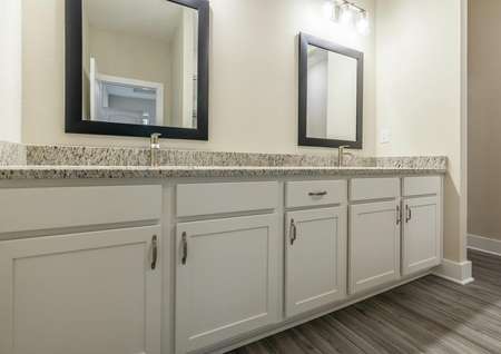 Double sinks with granite countertops and white cabinets with plenty of storage space.