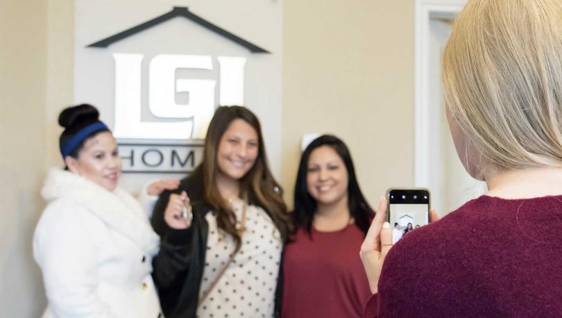 Group of women smiling while holding a set of keys and getting their photo taken. 