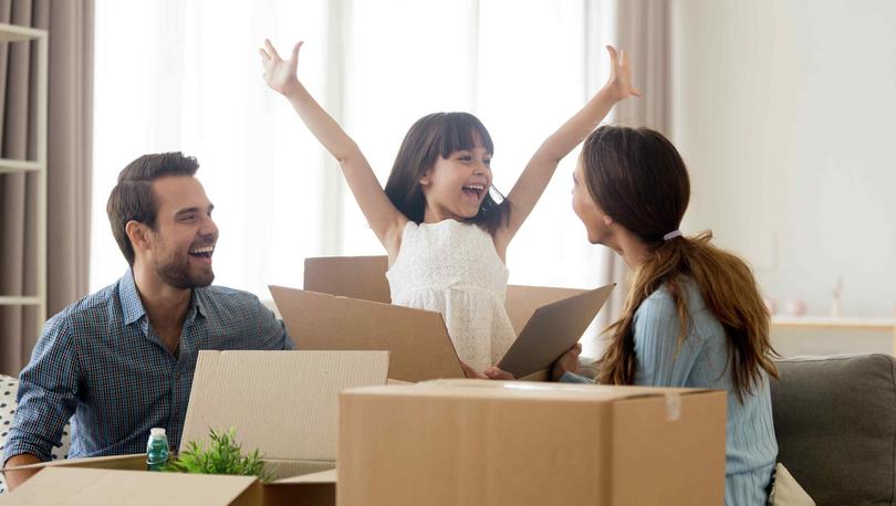 Family unpacking boxes, happy girl with arms in air