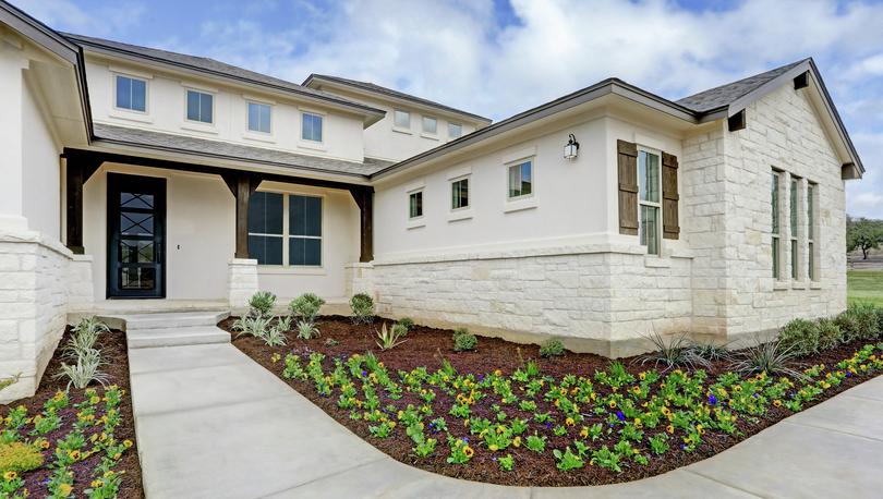 Beautiful stucco and stone Hampton plan with bright flowers.