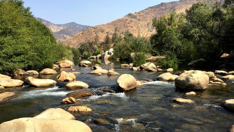 Bakersfield, California Kernville Kern River with large boulders throughout the river, trees lining the banks, and mountains in the distance