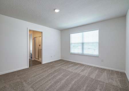 The carpeted master bedroom has one large window and its own full bathroom. 