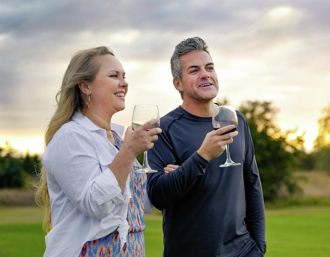 Couple drinking wine and admiring something in the distance at sunset.