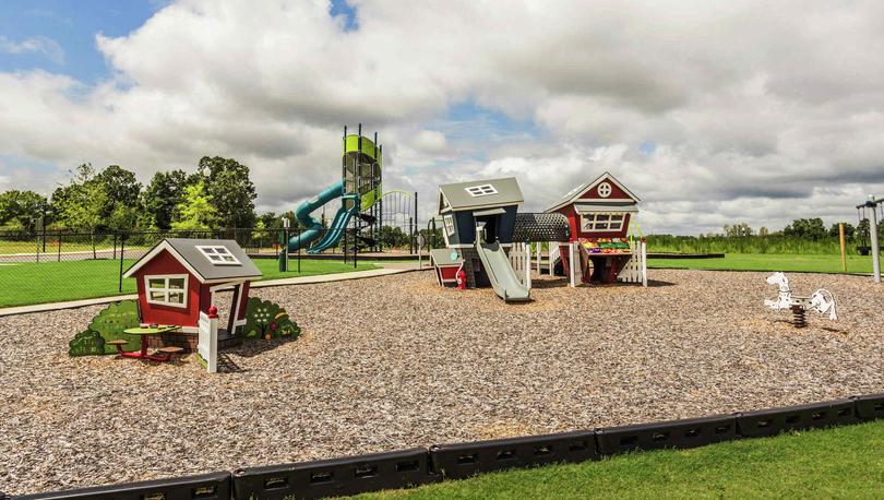 Playset for toddlers that look like little barn houses and a rocking horse on a wood chip surface in the Autumn Lakes community.