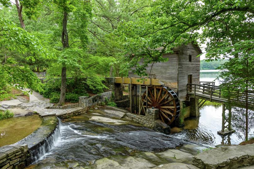 Atlanta, Georgia Grist Mill in Stone Mountain State Park with water flowing over rocks, large watermill, and overgrown green trees