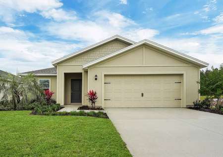 The exterior view of the St. Martin floor plan that is painted white, has a green front door and a decorative two-car garage.
