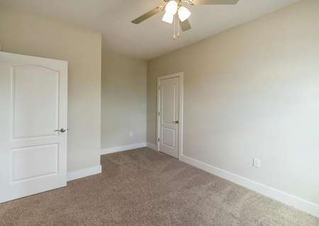 Guest bedroom with a ceiling fan and lots of natural light entering through the window.