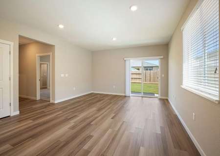 Incredible open family room with back yard access, wood style flooring and tan walls.