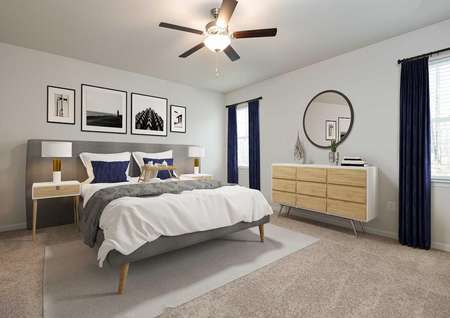 Staged master bedroom with king bed and dresser, modern decor in gray and navy, round mirror over dresser, ceiling fan and drapes on windows.