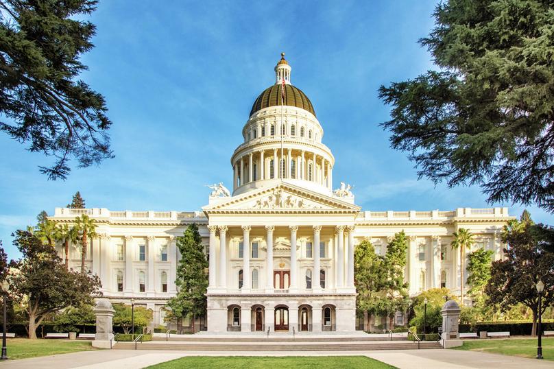 Sacramento, California state capitol building with white columns, brown dome, and beautifully-landscaped grounds